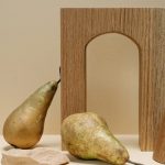 A minimalist still life composition featuring pears with geometric wooden shapes on a beige background.