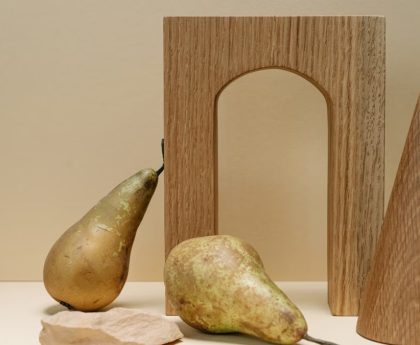 A minimalist still life composition featuring pears with geometric wooden shapes on a beige background.