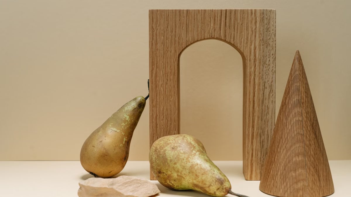 A minimalist still life composition featuring pears with geometric wooden shapes on a beige background.