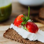 Rye bread topped with cream and juicy strawberries, perfect for a sweet treat.