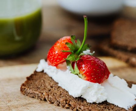 Rye bread topped with cream and juicy strawberries, perfect for a sweet treat.