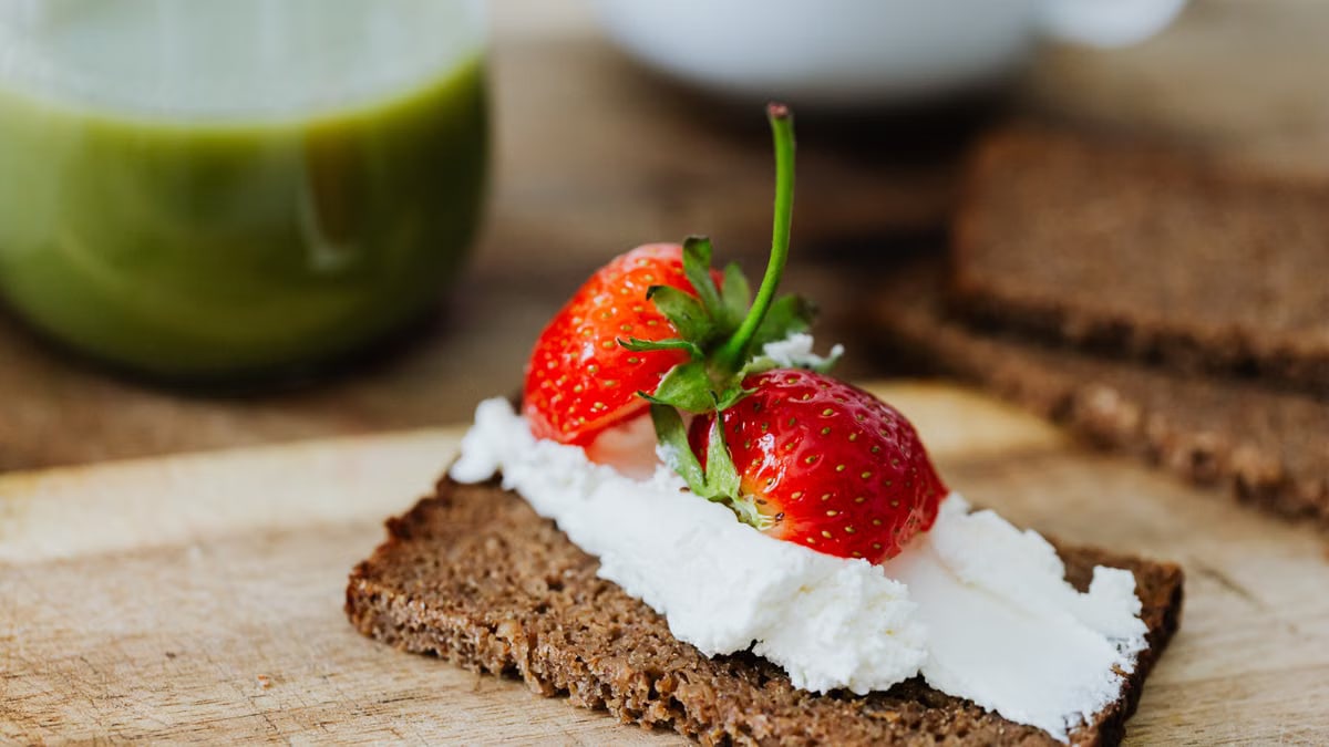 Rye bread topped with cream and juicy strawberries, perfect for a sweet treat.