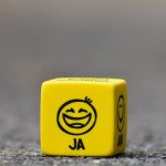 Close-up of a yellow dice featuring a smiley face emoticon symbolizing happiness and fun.