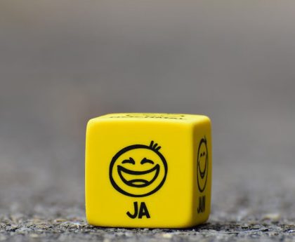 Close-up of a yellow dice featuring a smiley face emoticon symbolizing happiness and fun.