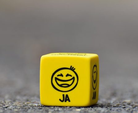 Close-up of a yellow dice featuring a smiley face emoticon symbolizing happiness and fun.