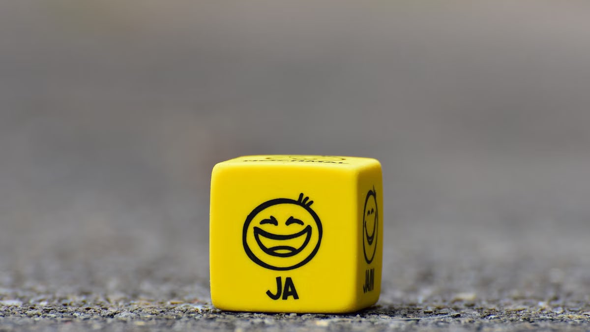 Close-up of a yellow dice featuring a smiley face emoticon symbolizing happiness and fun.